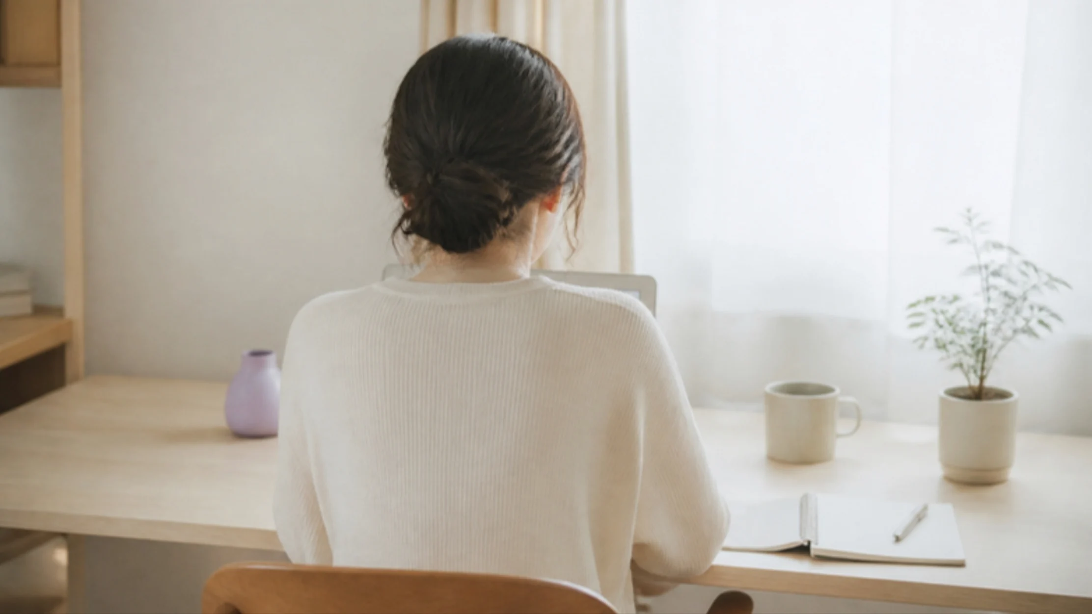 自宅の机でノートを広げ、オンラインセッションに向かう人の後ろ姿